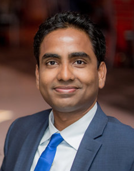 A man in a suit and tie smiling for the camera.